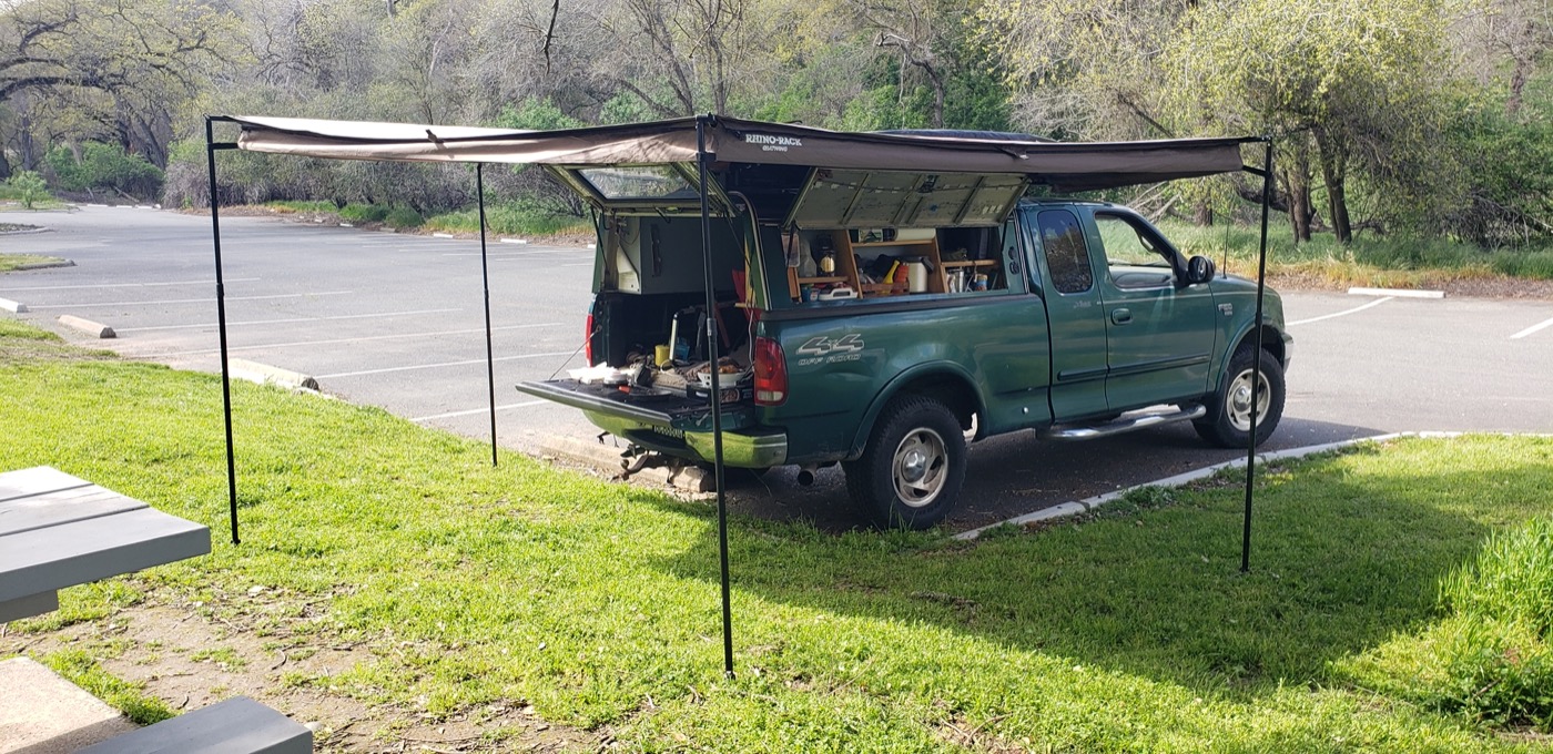 Roger's Ford F-150 adventure truck with a Rhino-Rack Batwing awning deployed and the camper shell open showing organized gear storage