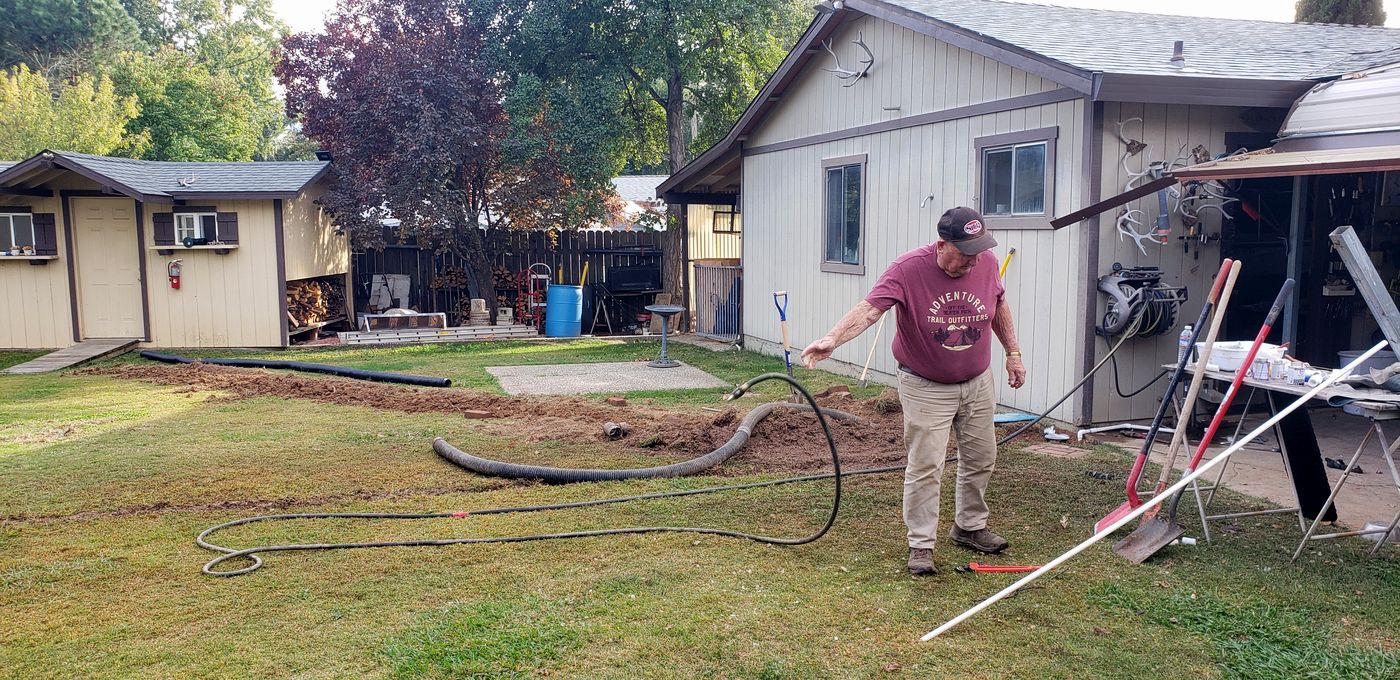My dad, wearing an ADVENTURE t-shirt, working on a drain line project in the backyard