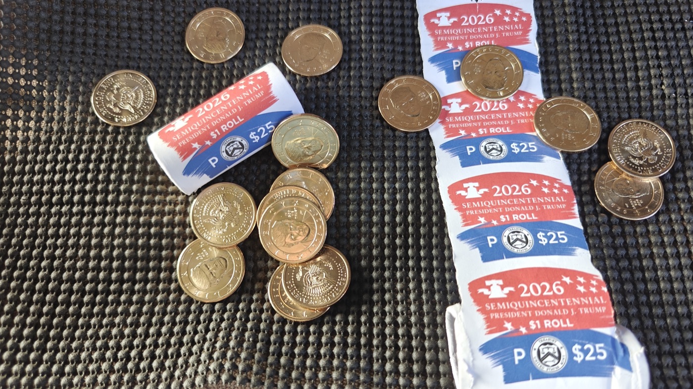 2026 Semiquincentennial Trump $1 coin rolls with loose coins scattered nearby
